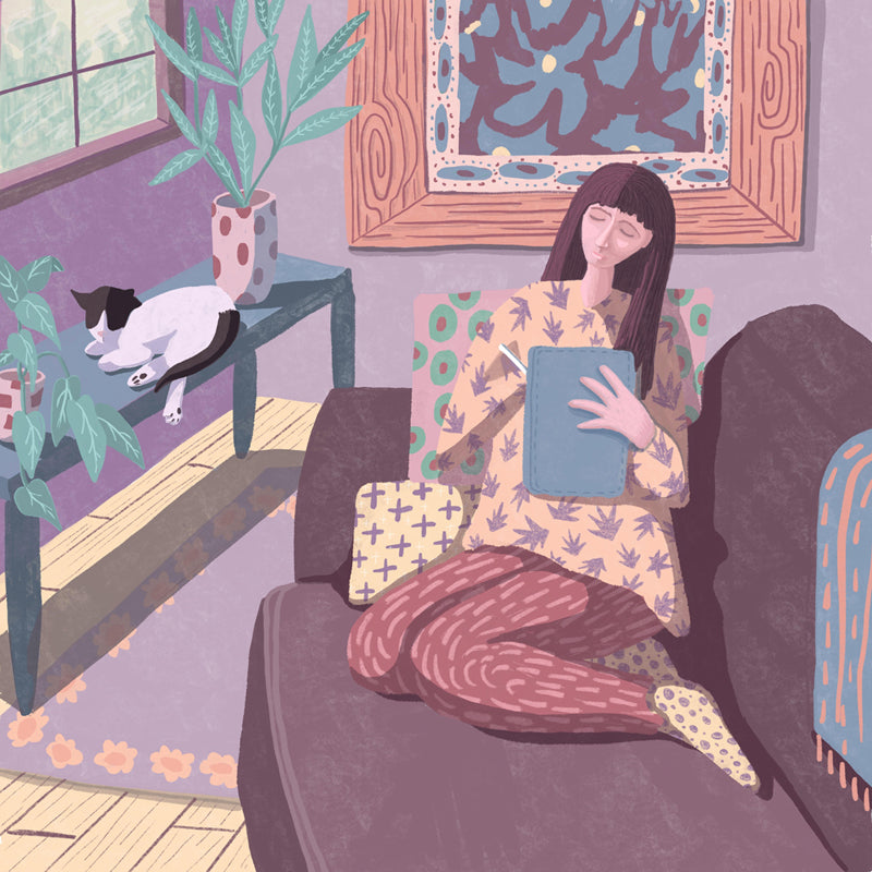 A woman sits peacefully on her couch drawing on an iPad surrounded by her plants, artwork and tuxedo cat.