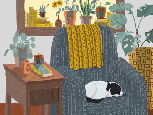 A tuxedo cat sleeps in a cozy chair in a room full of plants and books